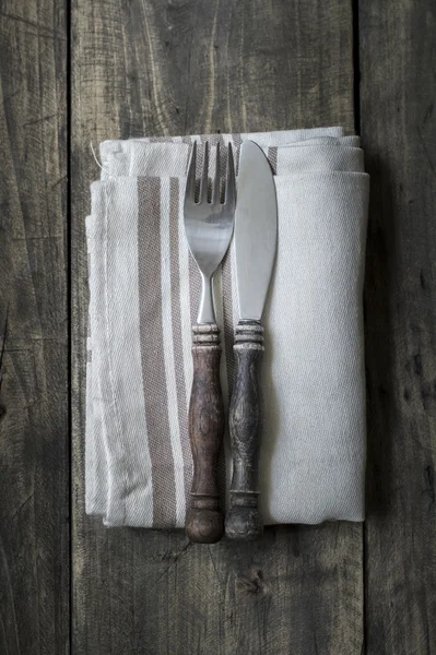 Cuchillo y tenedor en servilleta sobre tabla de madera — Foto de Stock