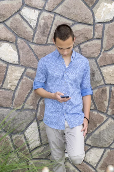 Retrato de un joven guay leyendo un mensaje de texto en su celular — Foto de Stock