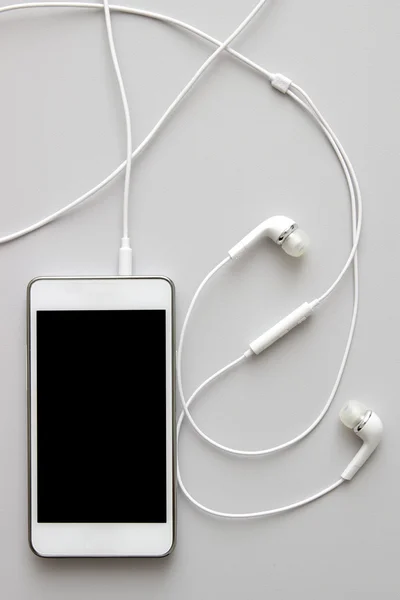 White smart phone with earphones and isolated screen on table — Stock Photo, Image