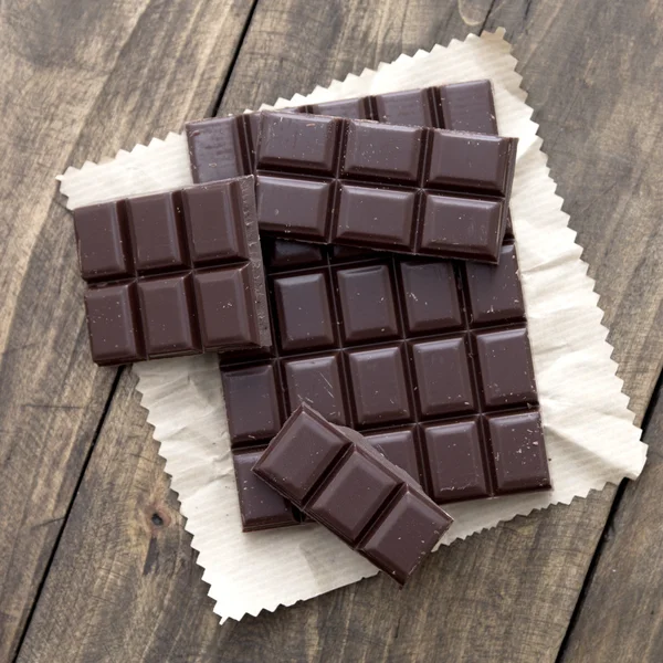 Gebroken chocolade bar op houten tafel. — Stockfoto