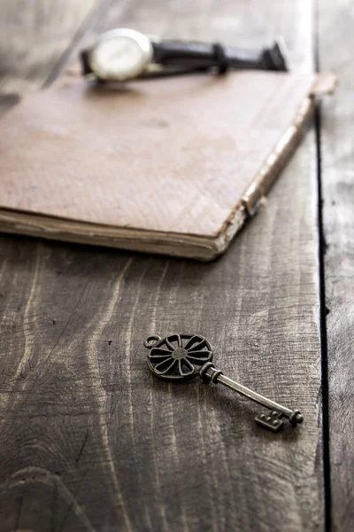 Old book and a brass key on a vintage surface — Stock Photo, Image