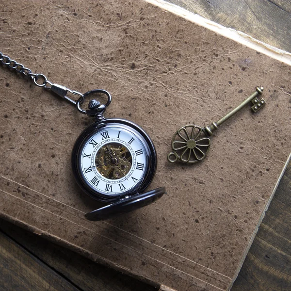 Antique book and pocket watch on grunge wooden table — Stock Photo, Image