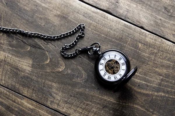 Pocket watch on grunge wooden table — Stock Photo, Image