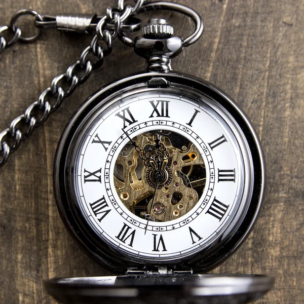 Pocket watch on grunge wooden table — Stock Photo, Image