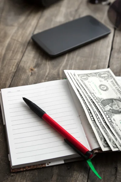 Blank notebook with dollar and smarthphone — Stock Photo, Image