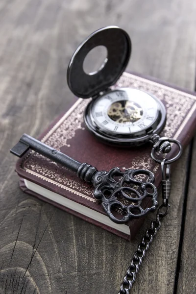 Zegarek kieszonkowy i stary klucz na drewnianym stole — Zdjęcie stockowe