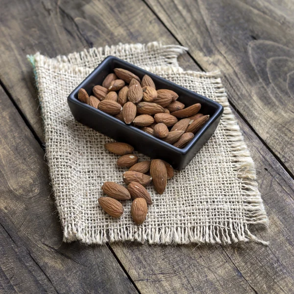 Almonds in  bowl on grained wood background — Stock Photo, Image