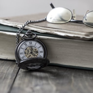 Bir antika köstekli saati, gözlük ve İncil 