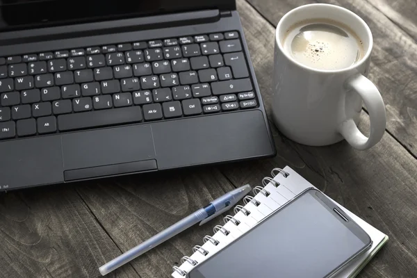 Γραφείο επιφάνεια εργασίας με καφέ, σημειωματάριο και lap-top. — Φωτογραφία Αρχείου