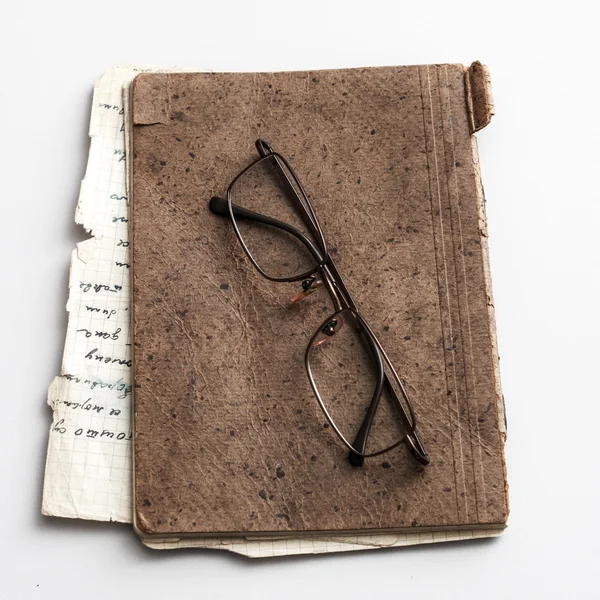 Очки и старая тетрадь на столе — стоковое фото