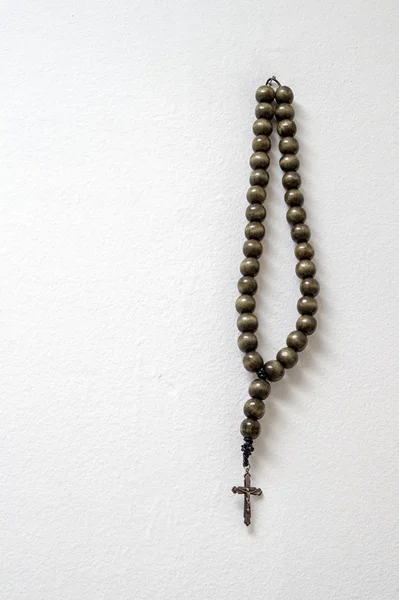 Rosary beads hanging against white wall — Stock Photo, Image