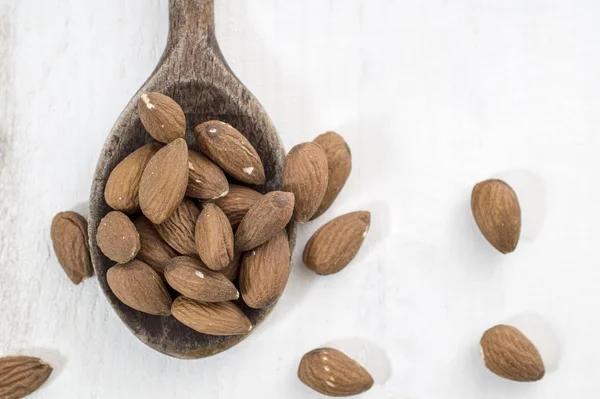 Almonds, white wooden table background — Stock Photo, Image