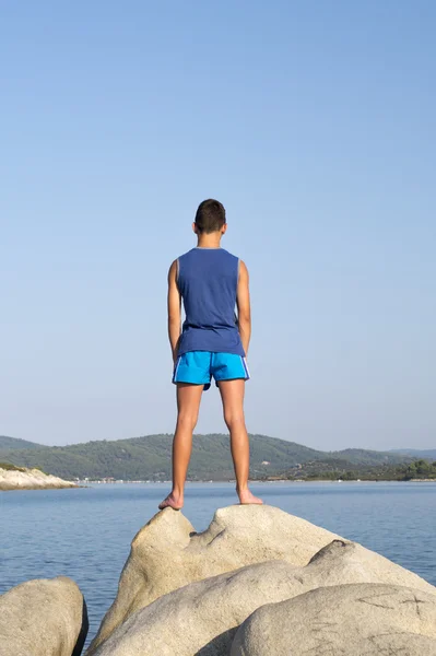 Garçon debout sur un rocher au bord de la mer . — Photo