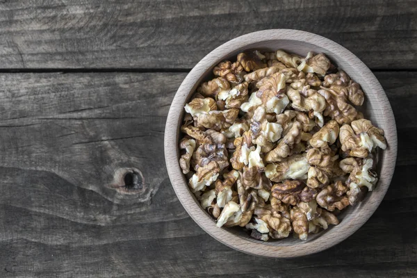 Valnötter i trä skål på träbord — Stockfoto