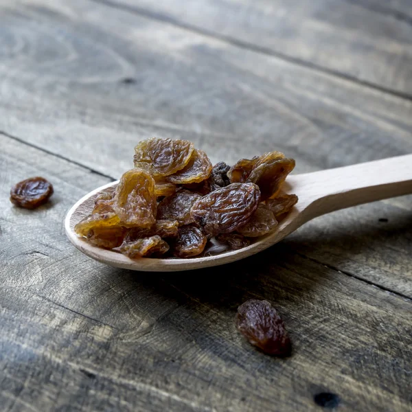 Läckra små svarta russin på en träslev — Stockfoto