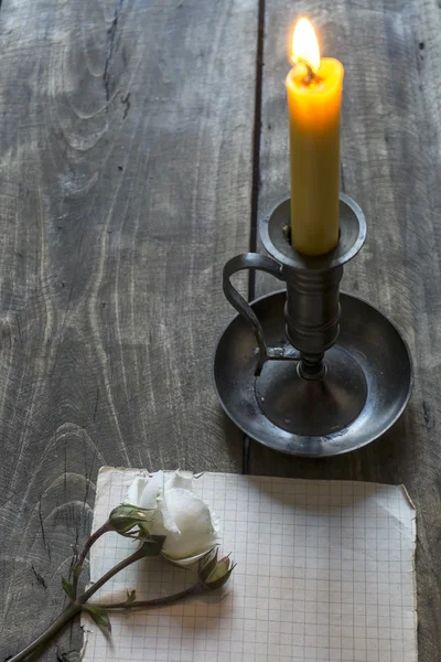 Old sheet of paper, pink rose  and candle on wooden background. — Stock Photo, Image