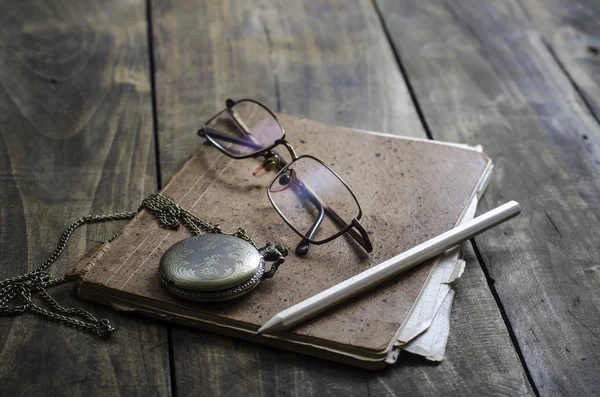 Cep saati, gözlük ve masa üstünde eski defter — Stok fotoğraf