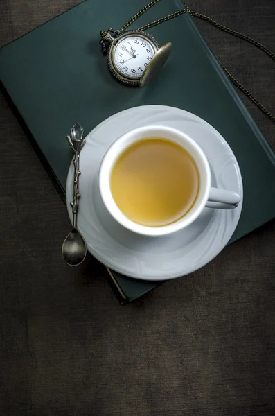 Taza de té y libro sobre mesa de madera — Foto de Stock