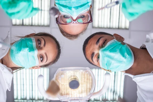 Equipe dentária trabalhando com um paciente em desgaste de trabalho de proteção — Fotografia de Stock