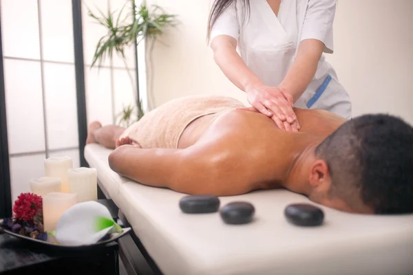 Masseur doing back massage with spa stones on man body in the sp — Stock Photo, Image