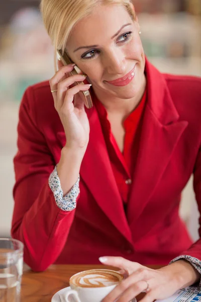 Middelbare leeftijd zakenvrouw met behulp van een mobiele telefoon in de coffeeshop — Stockfoto