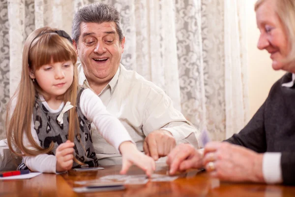 Feliz pareja de ancianos con nieta jugando a las cartas —  Fotos de Stock