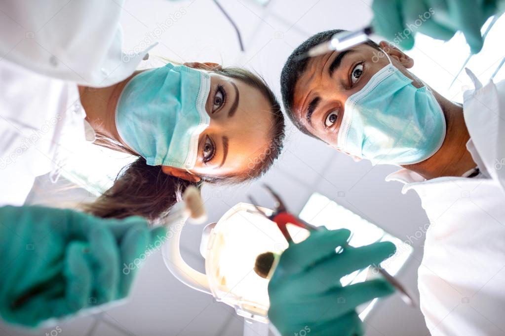 Dental team working with a patient in protective work wear