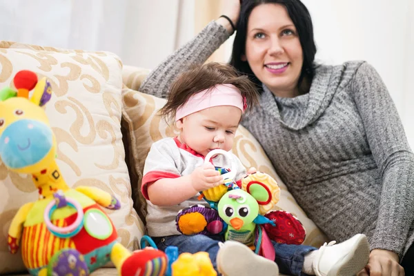 Hübsche junge Mutter spielt mit ihrem Baby im Zimmer — Stockfoto