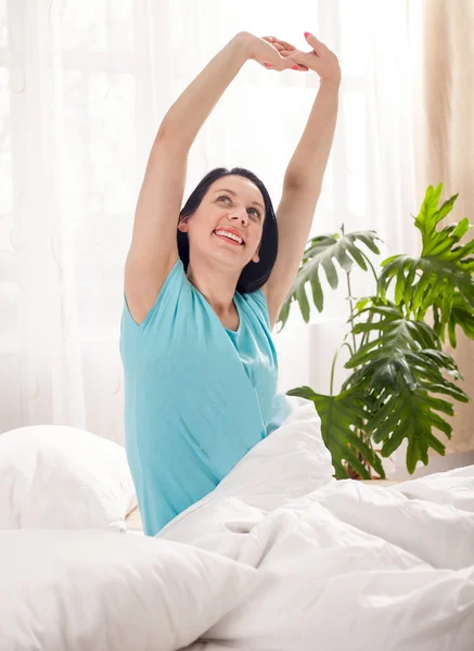 Счастливая женщина растягивается в постели после пробуждения — стоковое фото