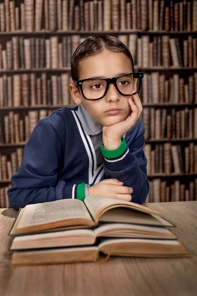 Unga fifflare med glasögon eller geni i bibliotek behandlingen bok — Stockfoto