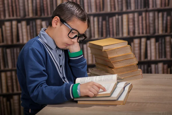 Un joven genio leyendo un libro en la biblioteca — Foto de Stock