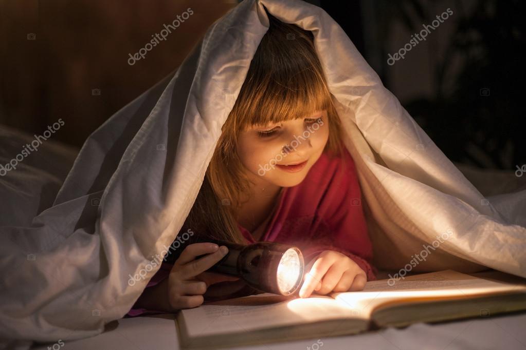 чтение в темноте. чтение под одеялом с фонариком. девочка с книжкой и фонариком под одеялом. чтение под одеялом. чтение книги под одеялом.