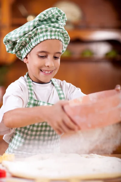 Jovem engraçado menino brincando com a farinha na cozinha — Fotografia de Stock