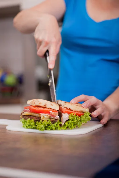 Woman cuts home made burger — Stock Photo, Image