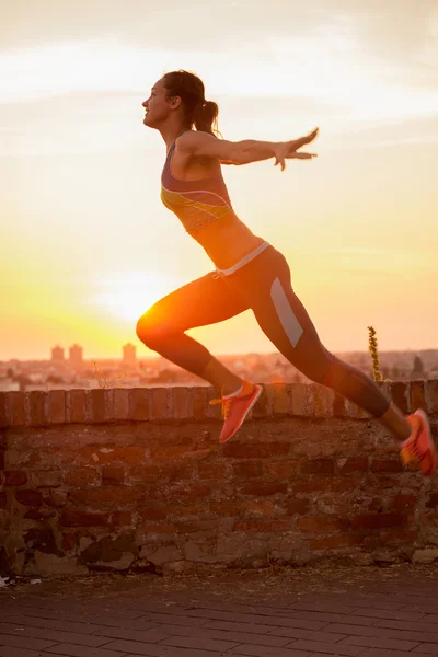 Saltando ragazza silhouette in tramonto — Foto Stock