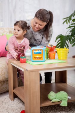 Anne ve genç kızı oturma odasında oyuncaklarla oynamak 