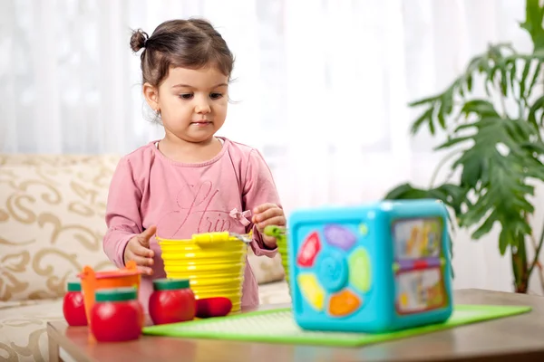Милая маленькая девочка, играющая с игрушкой в комнате — стоковое фото