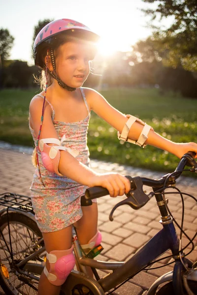 Portret van het meisje in roze veiligheidshelm op haar fiets in park — Stockfoto