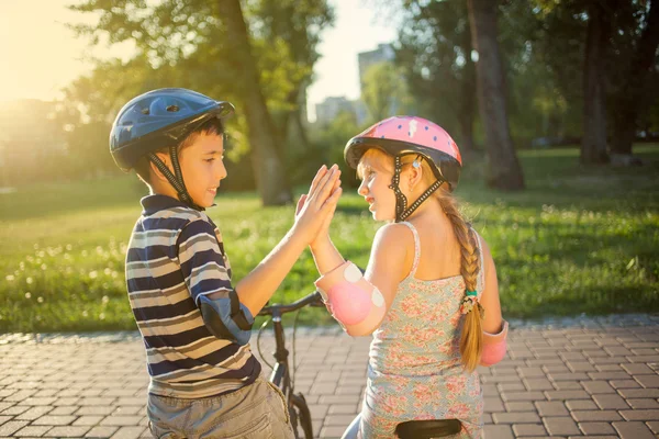 Meisje en jongen rijden fiets in park — Stockfoto