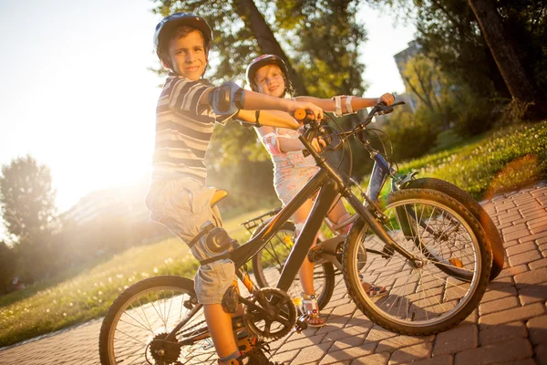 Gelukkig smilling meisje en jongen paardrijden fietsen in park — Stockfoto