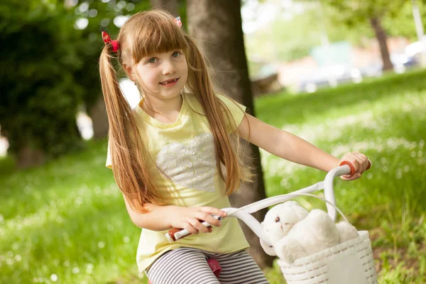 Piccola scuola-ragazza va in bicicletta nel parco — Foto Stock