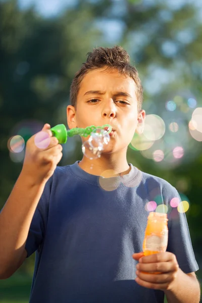 Boy blowing soap bubbles in summer park — Stock Photo, Image