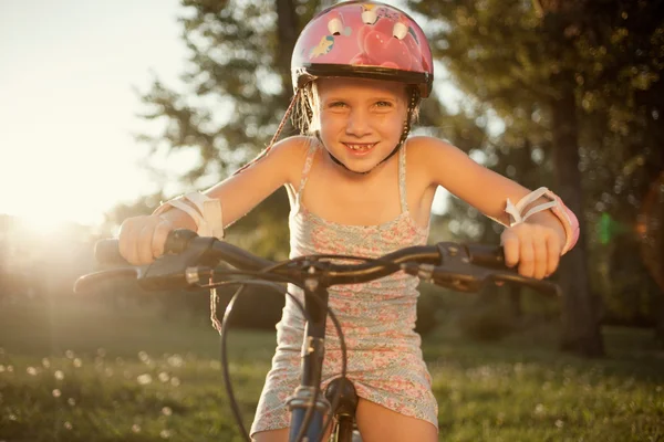 Portrait of girl in  pink safety helmet on her bike in park — Stock Photo, Image