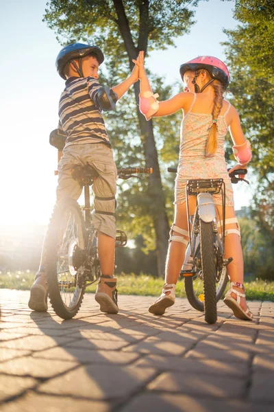 Glad flicka och pojke ridning cykel i park — Stockfoto