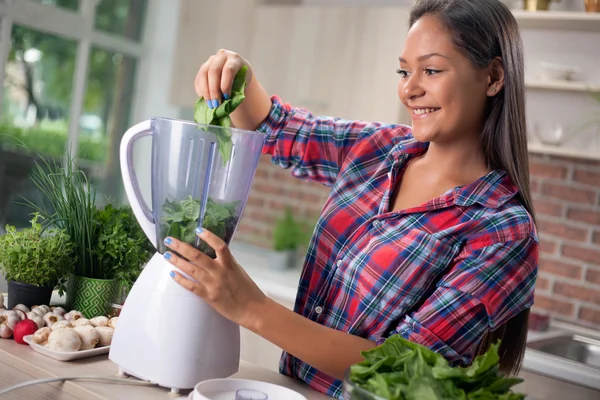 Junge Frau mit Mixer hackt grünes Gemüse für Detox-Sha — Stockfoto