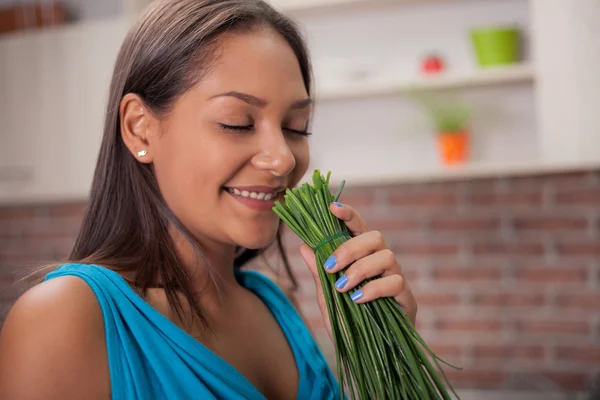 Mulher sorridente na cozinha com legumes orgânicos cebolinha — Fotografia de Stock