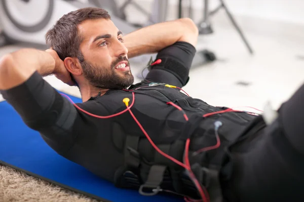 Ejercicio de hombre joven en forma en la máquina de estimulación electro muscular —  Fotos de Stock