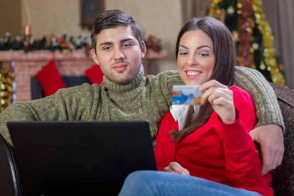 Młoda para zadowolony za pomocą karty kredytowej do e sklepu na Boże Narodzenie nig — Zdjęcie stockowe