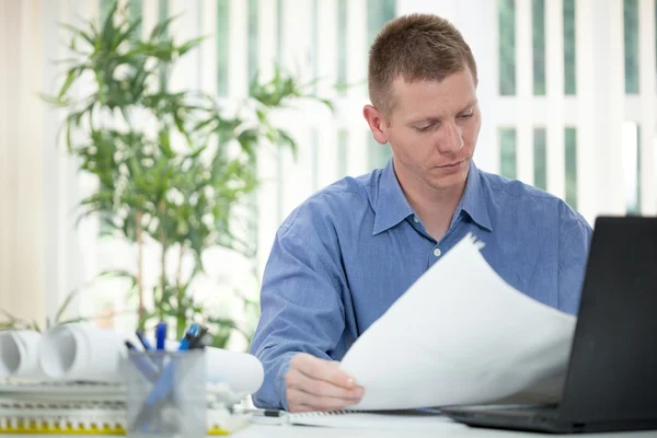 Homme d'affaires concentré analysant des graphiques dans son bureau — Photo