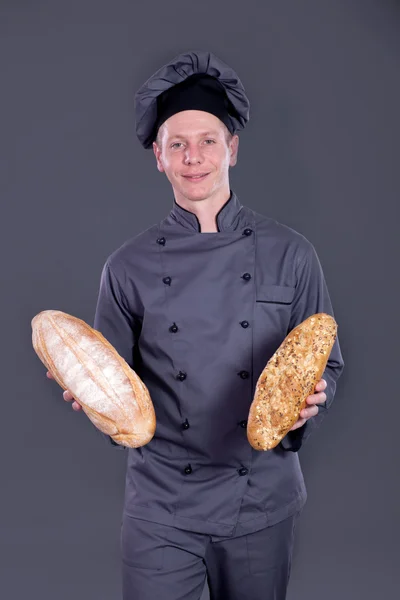 Σεφ παρουσιάζει ψωμί στο χέρι του σε γκρι φόντο — Φωτογραφία Αρχείου